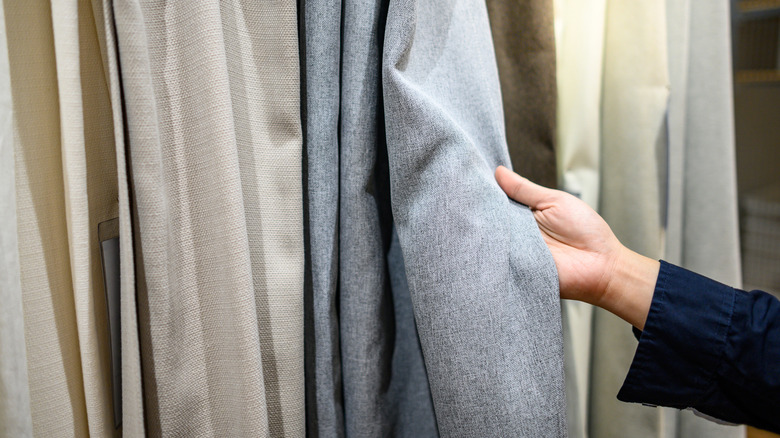 Image of a hand choosing between various natural curtains in a shop