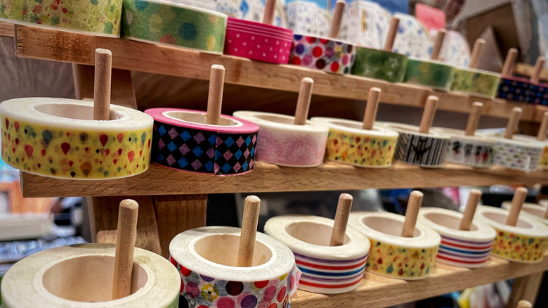 Multiple rolls of washi tape with various patterns and colors on wood display pegs