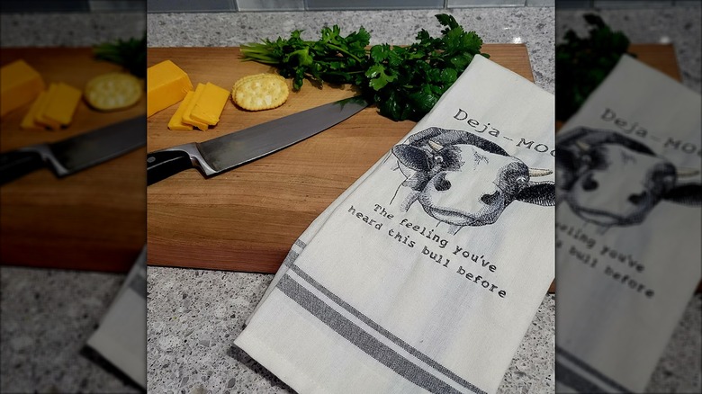 Cutting board with knife, food, and a white towel with a pun on it