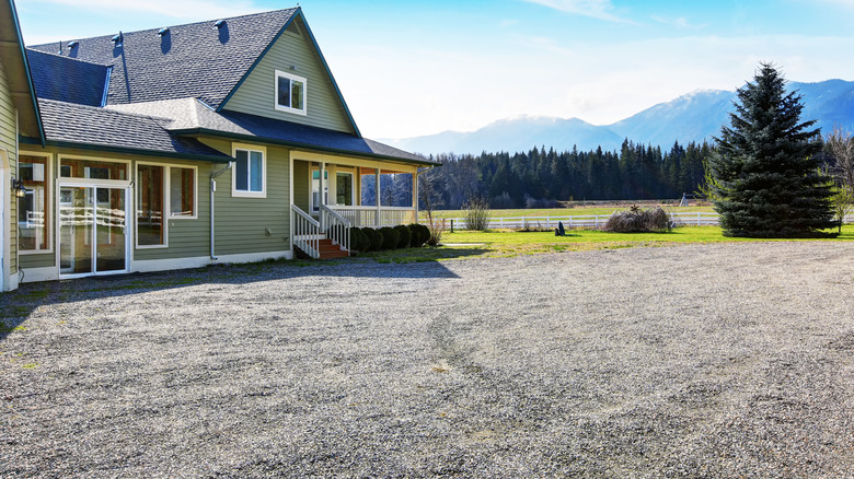 A green house with a large gravel driveway