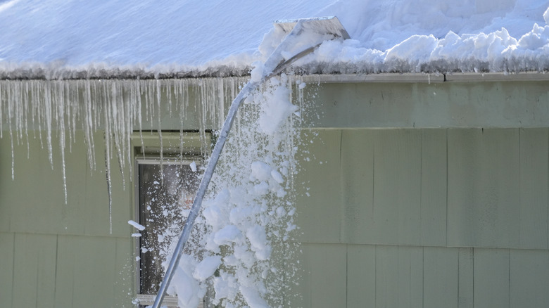 A person removes icicles from a roof