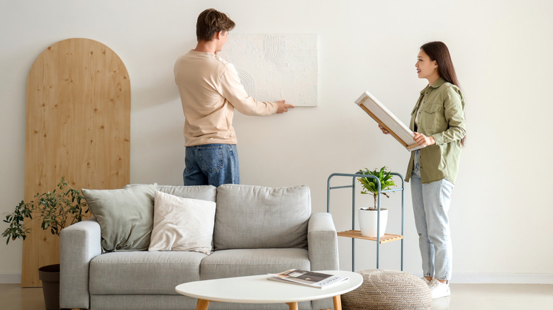 A couple hanging minimalist white art on white walls