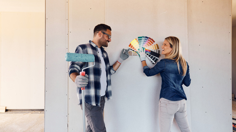 A smiling couple choosing paint color for their home