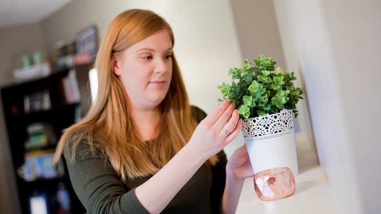 woman arranges fake plant decor