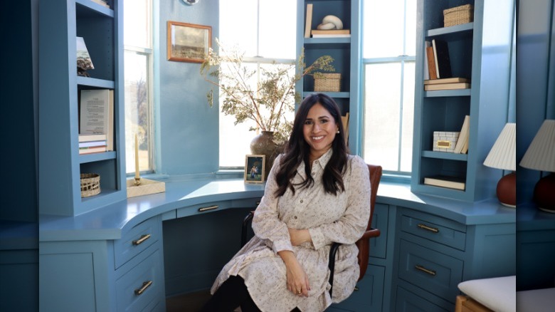 Fariha Nasir smiling in office with blue desk and shelves