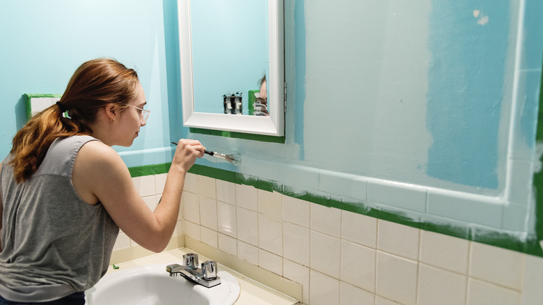 Woman painting bathroom backsplash