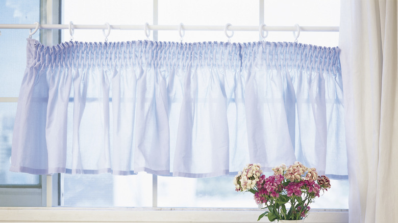 Light blue cafe curtain hanging in window