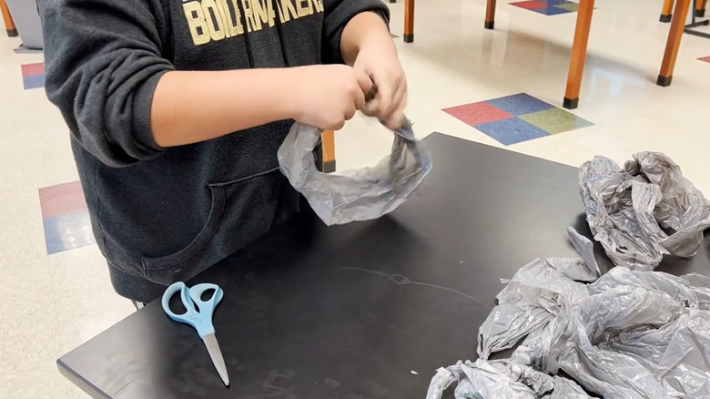 Person cutting plastic bags into loops to make plarn