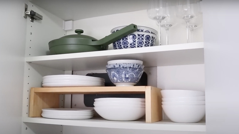 A shelf riser is placed in a cabinet