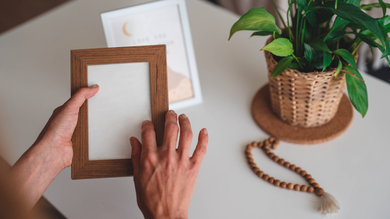 A person holding an empty wood picture frame