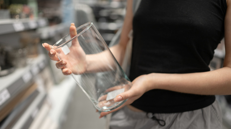 Woman holding empty glass vase in store