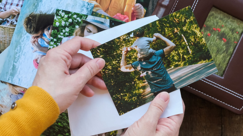 Person sorting photos with photo album in back