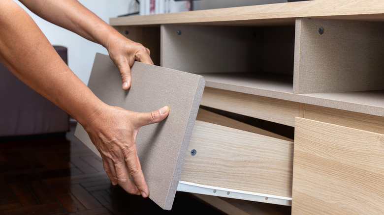 A person removing a drawer from a cabinet