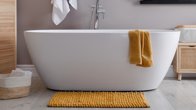 Deep tub with yellow towel and mat