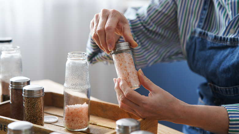 A woman transfers spices into different bottles.