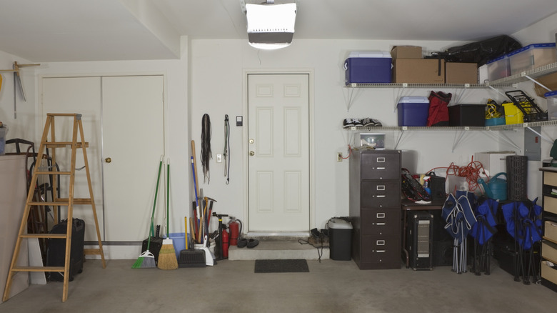 A home garage with a ladder, cleaning tools, and storage