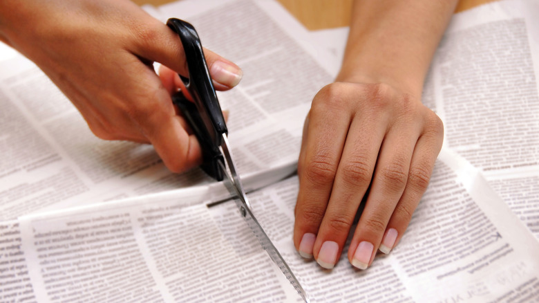 person cutting newpaper