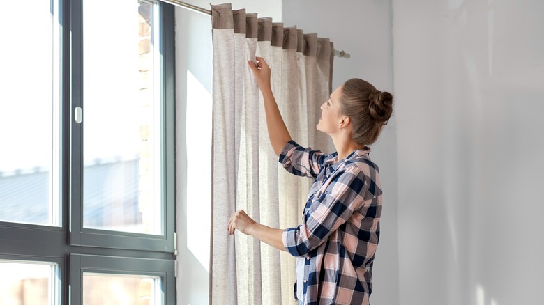 Woman creating pleats in curtain