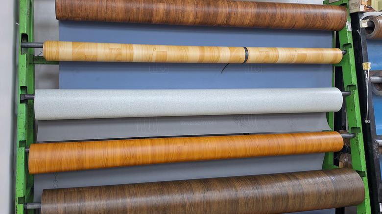 Rows of faux woodgrain vinyl hang in a factory