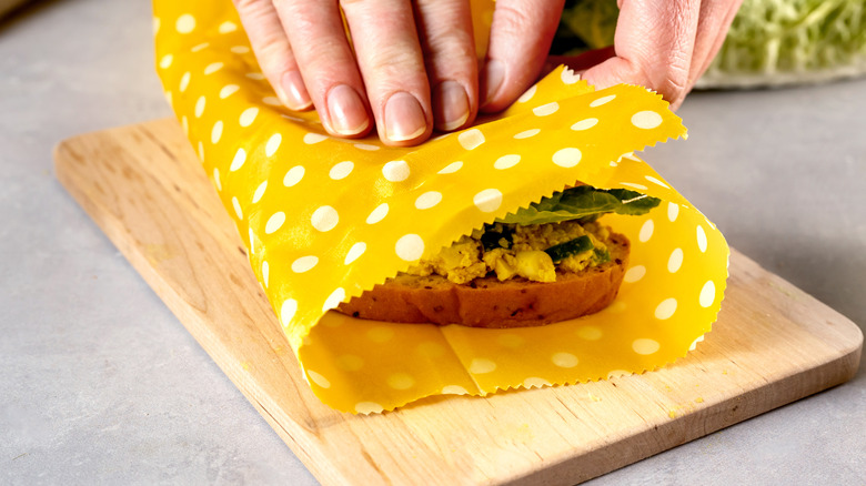 Hands wrapping a sandwich with reusable wrap