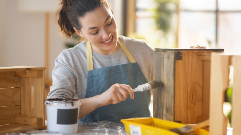 Woman staining wooden crate