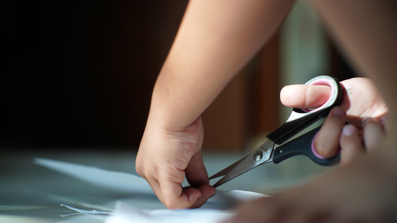 Person cutting paper with scissors