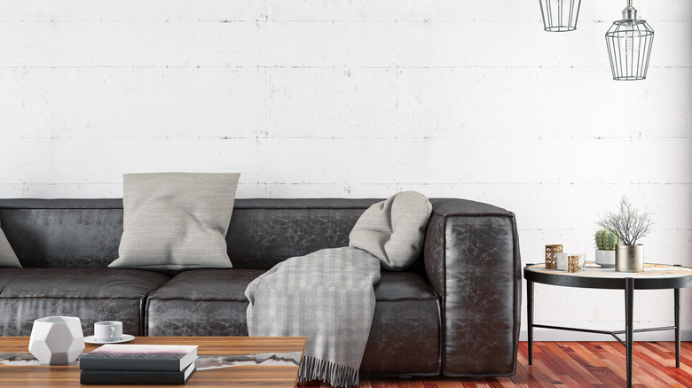 dark grey couch white wall and light grey pillows