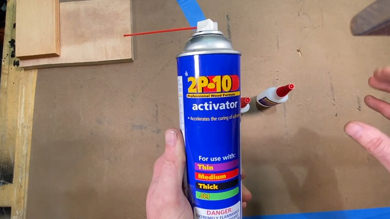 Hand holding activator spray in a wood workshop