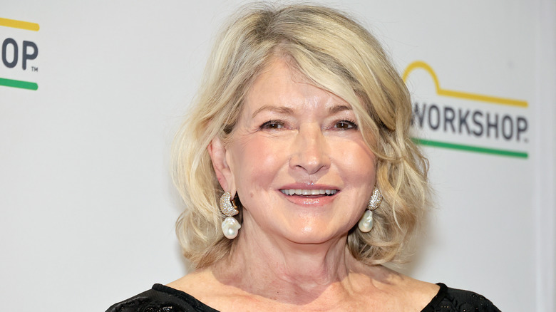 Martha Stewart with pearl earrings smiling in front of a workshop banner