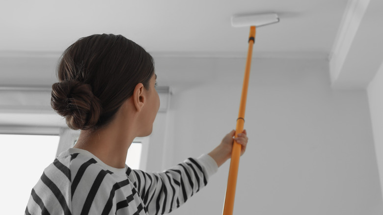 woman painting ceiling with roller