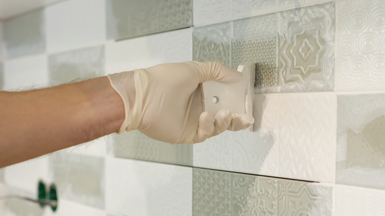 Person applying grout to checkered backsplash