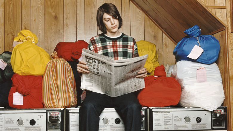 person reading newspaper on washing machines 