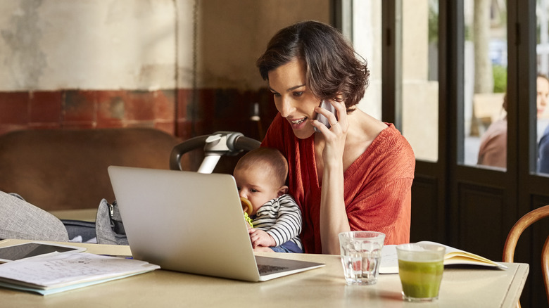 woman checking computer, holding baby 