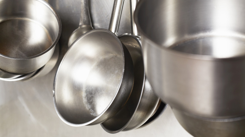 Array of hanging stainless steel pans with slight wear on bottom