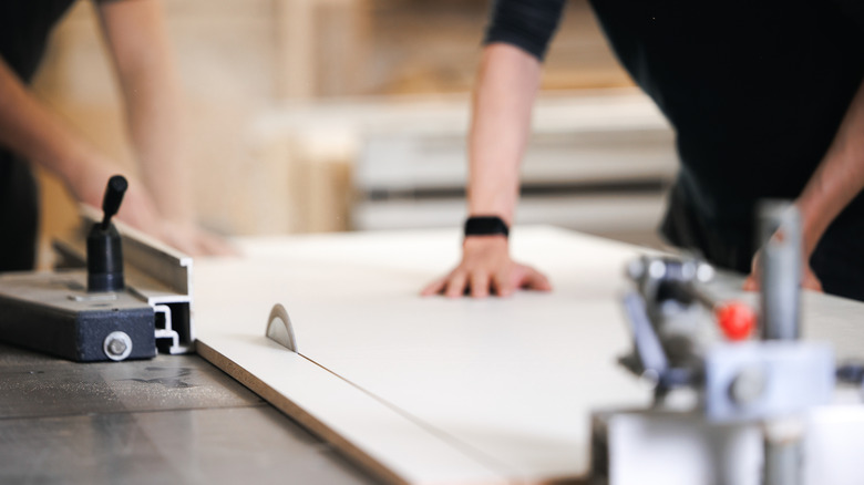 Two people using table saw to cut wood