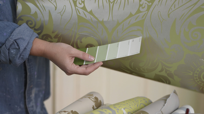 Person matching paint colors to wallpaper