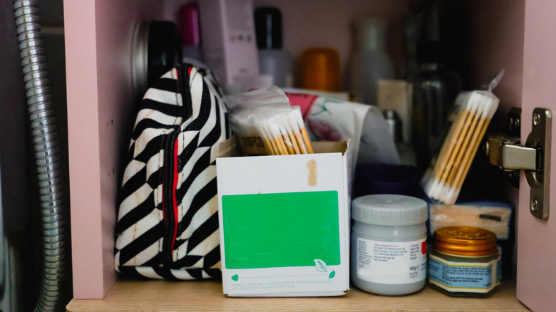 Toiletries are shoved into a messy bathroom cabinet