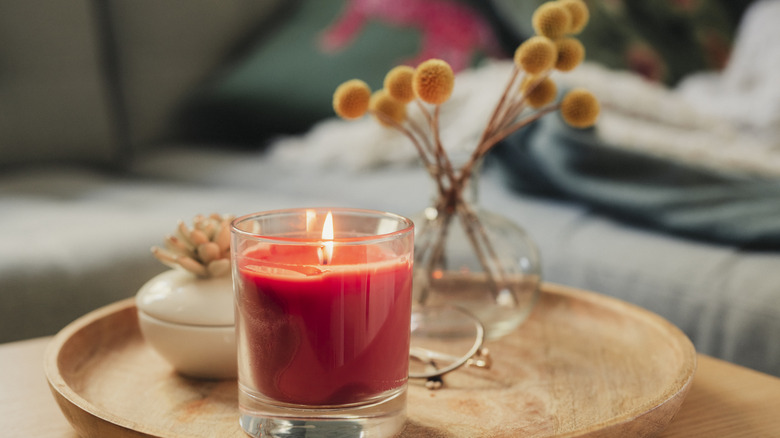 Decorative red candle on wooden tray in home with other decorative items