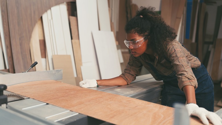 Woman cutting plywood in shop