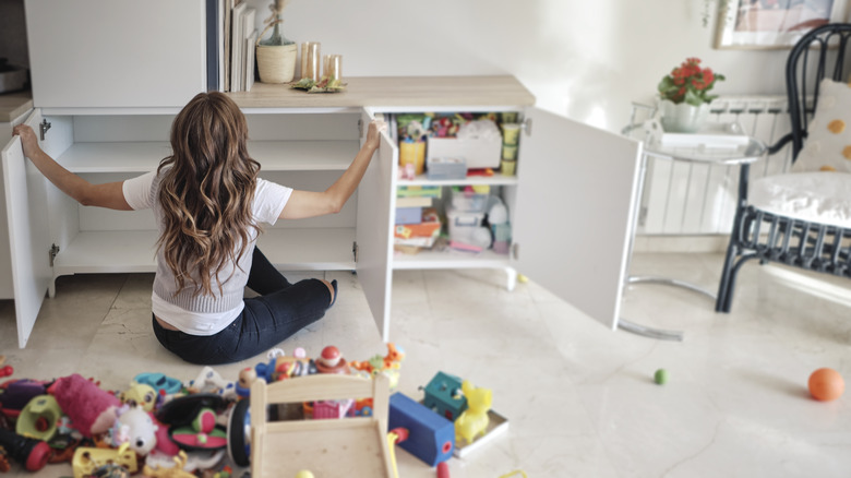 Person organizing cluttered cabinet