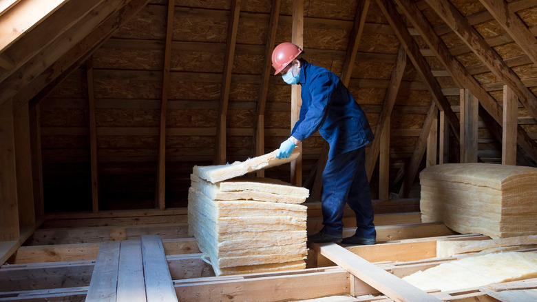 Person puts sections of insulation in the attic