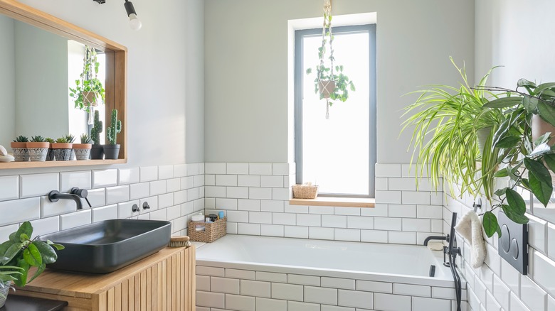 White tile bathtub in bathroom with potted plants