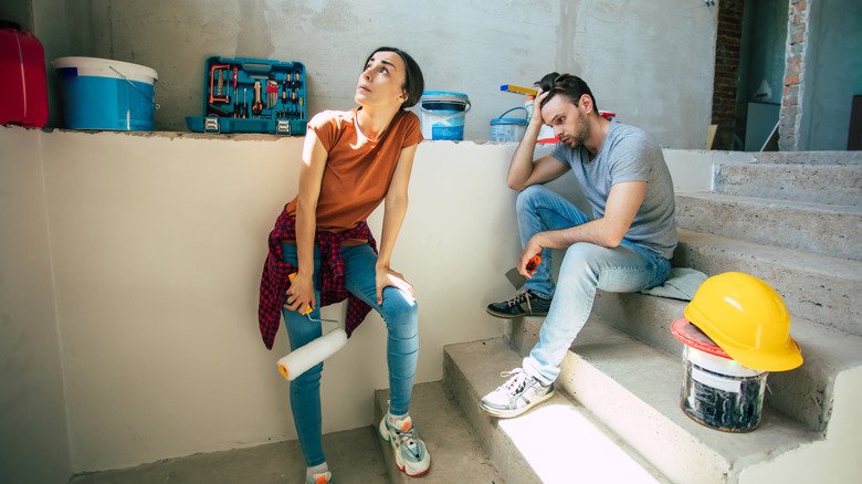 Woman and man looking stressed in room under renovation