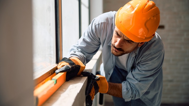 Man in hard hat using a level on a window frame