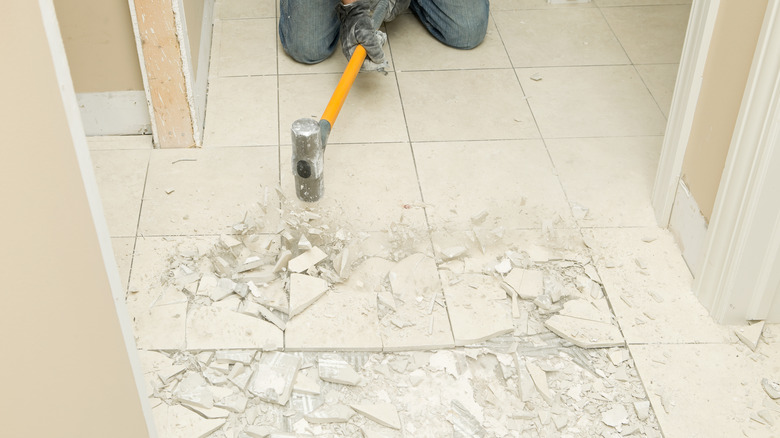 Smashing floor tiles with sledgehammer