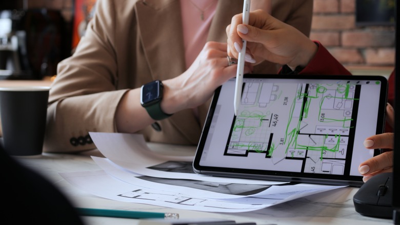 Hands holding tablet with architectural plans on screen