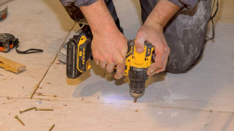 Person drilling into plywood subfloor