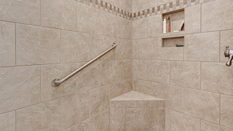 tiled shower with grab bar in the corner