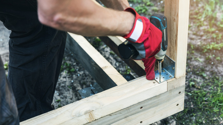 Man screwing on a brace while building a base