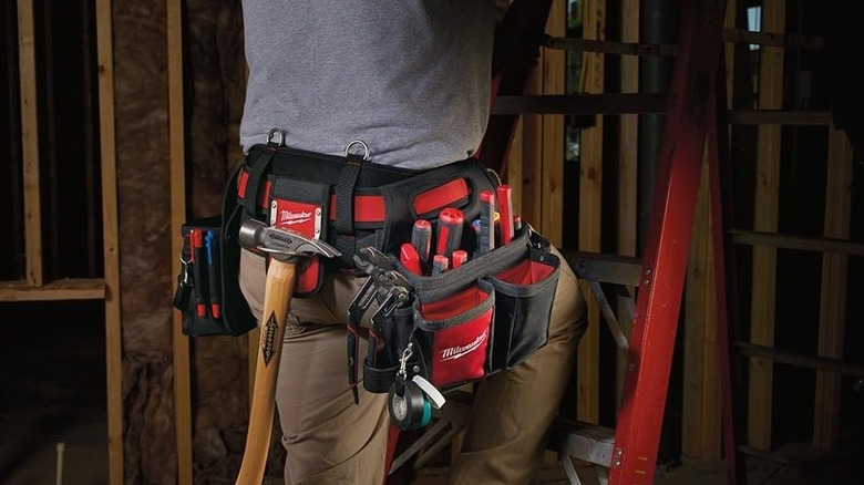 Person wearing a Milwaukee tool belt stocked with a hammer and much more